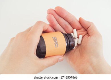 Person Taking Zinc Pills Out Of A Bottle. Close Up.