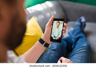 Person talking to a friend on his smartphone during an online video call while relaxing on the couch  - Shutterstock ID 2034132350