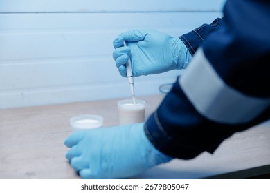 Person testing milk sample with lab equipment in clean environment, analysis for presence of antibiotics and acidity.