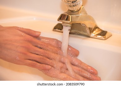 A Person Thoroughly Washing His Hands In Warm Soapy Water In An Old House. Outdated, Rusty, And Dirty Gold Faucet With Mold And Hard Water Mineral Deposits. Heavily Stained With Calcium And Lime.