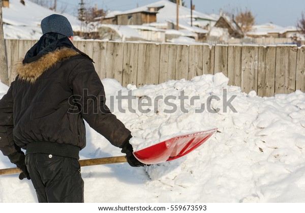 The
person throws a red shovel snow. Shovels away
snow