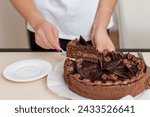 Person is transferring a slice of multi-layer chocolate cake to plate, showcasing cake