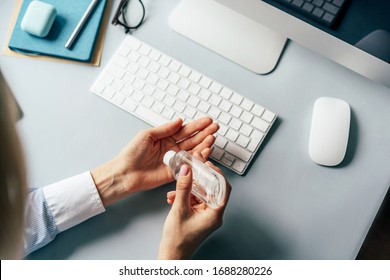 A person treats hands with a disinfector over a working office desk. Self-isolation and hygiene in the epidemic of coronavirus. Stay at home in quarantine and work remotely from home. - Powered by Shutterstock