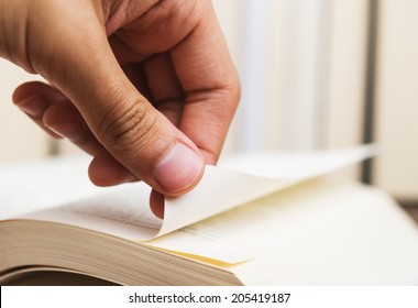 Person Turning The Page Of A Book Up Close