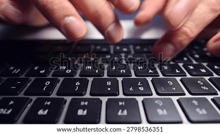 A person types on a black computer keyboard, focus on hands and keys