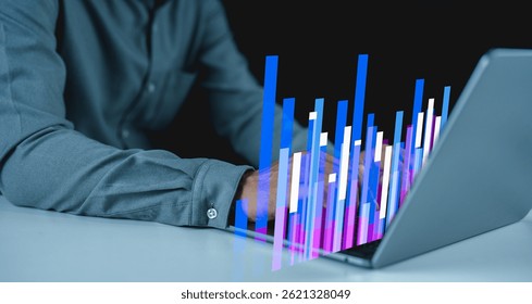 A person types on a laptop with colorful, digital bar graphs projected above the keyboard.