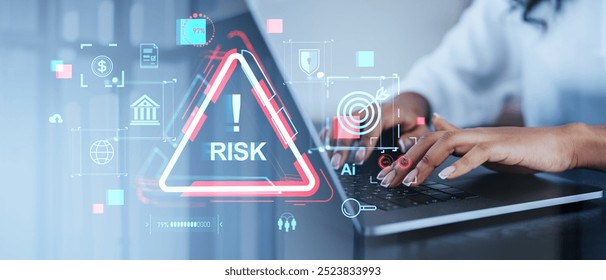 A person types on a laptop with holographic financial icons and a risk warning sign overlay. The background is blurred. The concept is risk management in a digital financial context - Powered by Shutterstock