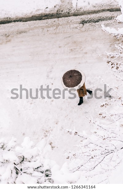 person with\
umbrella crossing the snowy\
street