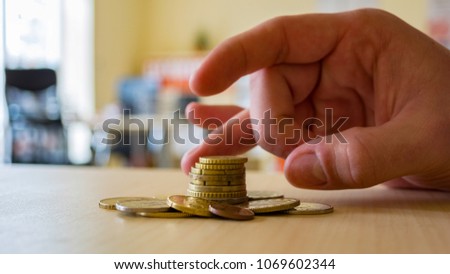 A person uses his fingers to flick a coin stack.