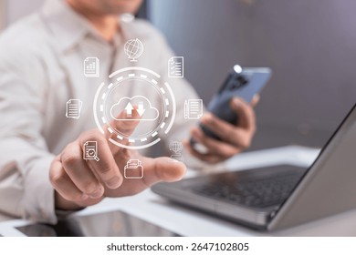 A person uses a smartphone and laptop with digital cloud storage and data icons overlay, symbolizing technology and data management.