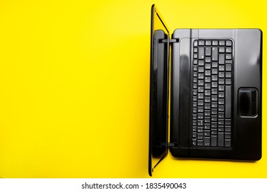 Person Using Black Laptop On A Yellow Desk. Above View. Copy Space. Studio Shot. Corporate Workplace Concept.