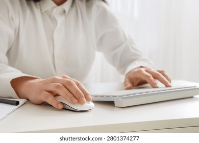 Person using computer mouse and keyboard at desk