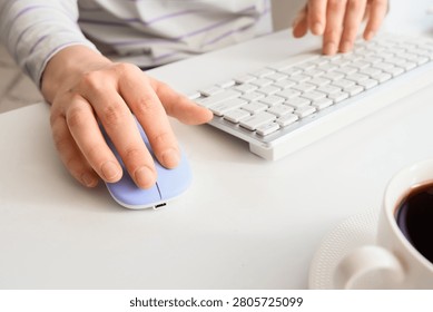 Person using computer mouse and keyboard with coffee cup