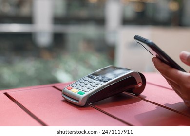 A person is using a credit card reader to pay for something. The person is also using a cell phone