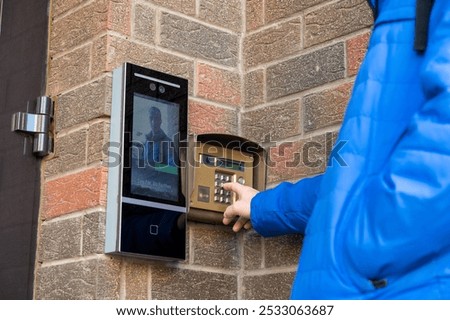 A person using a digital intercom system on a brick wall background, showcasing technology for entry access