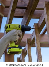 Person is using a drill to put a screw into a piece of wood. The person is holding the drill with their right hand and the screw is being driven into the wood with the drill