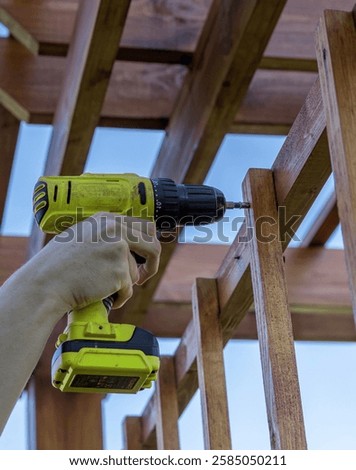 Person is using a drill to put a screw into a piece of wood. The person is holding the drill with their right hand and the screw is being driven into the wood with the drill
