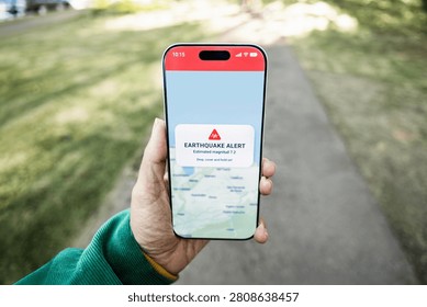 Person using earthquake app on mobile phone for real-time emergency alert - High magnitude warning