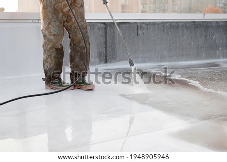A person using high-pressure equipment to clean the bottom of a water pool. Cleaning dirt. Before and after situation. Uniform and rubber boots.