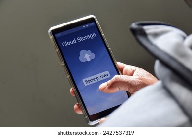 Person using his smartphone to upload and backup files to online storage or cloud storage service.