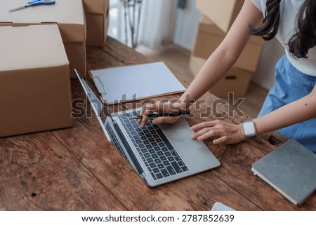 Person using laptop computer for e commerce with shipping boxes on wooden desk
