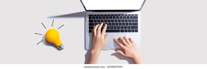 Person using a laptop computer and a light bulb - Flat lay