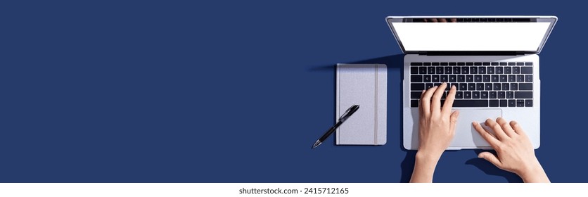 Person using a laptop computer with a notebook - Flat lay