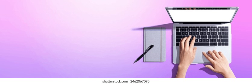 Person using a laptop computer with a notebook - Flat lay