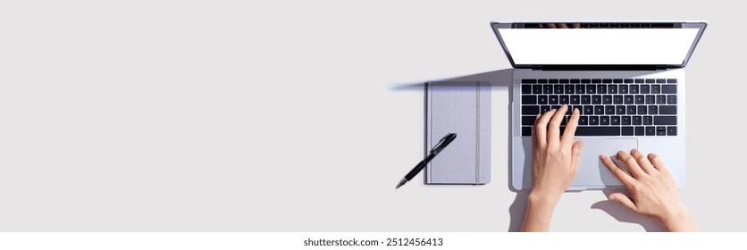 Person using a laptop computer with a notebook - Flat lay