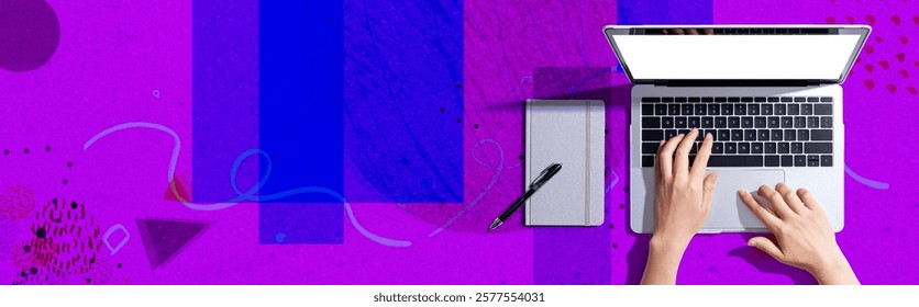 Person using a laptop computer with a notebook - Flat lay