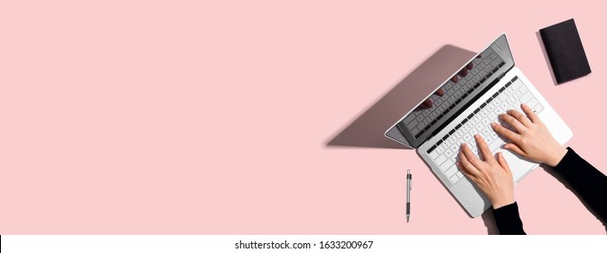 Person Using A Laptop Computer On A Solid Color Background