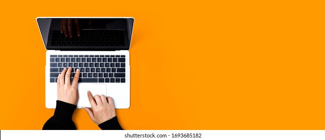 Person Using A Laptop Computer On A Solid Color Background