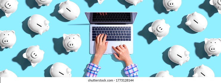 Person using a laptop computer with piggy banks - flat lay