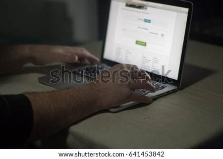 Person using laptop in dark room. Moody, sinister.