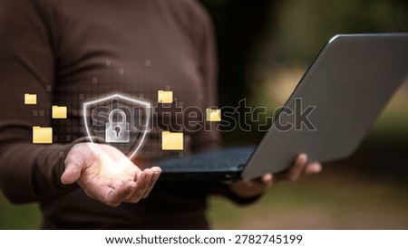 Person using laptop with digital security shield and protected folders interface, representing cybersecurity, cloud storage, data privacy and secure file management.