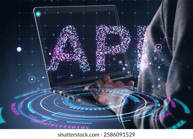 Person using laptop with glowing API text and futuristic holographic interface on dark background. Concept of digital network and cyber technology