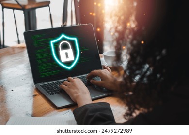 A person using a laptop with a glowing shield icon representing firewall protection and cybersecurity. Digital code in the background.