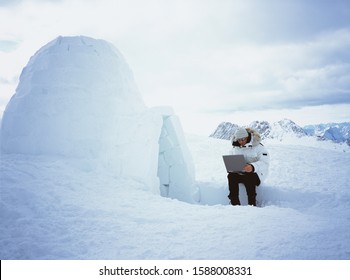 Person using laptop next to igloo