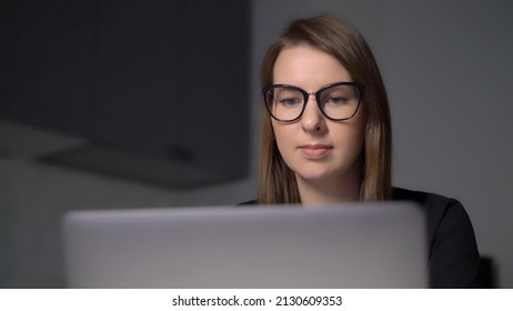 Person Using Laptop. Woman Working On The Computer, Typing Text On Keyboard. Electronic Device, Tablet On Table In The Kitchen. Remote Work Or Study From Home. Girl In Glasses At Night.