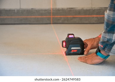 A person using a laser level tool on a smooth surface to ensure accurate measurements, showcasing the practicality of technology in construction and home improvement projects.