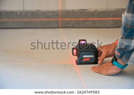 A person using a laser level tool on a smooth surface to ensure accurate measurements, showcasing the practicality of technology in construction and home improvement projects.