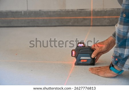 A person using a laser level tool on a smooth surface to ensure accurate measurements, showcasing the practicality of technology in construction and home improvement projects.