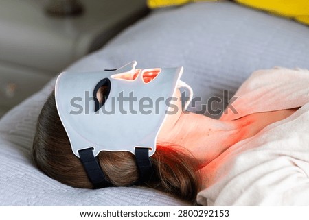 Person using LED light therapy mask at home