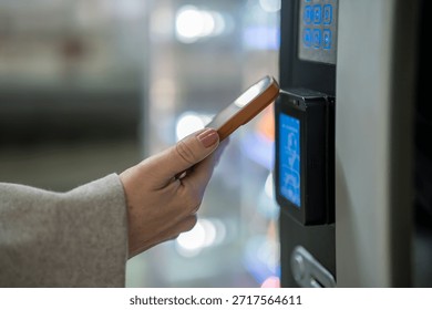 Person using mobile device for digital transaction, tapping near a payment terminal or vending machine, illustrating modern, convenient shopping and secure financial technology