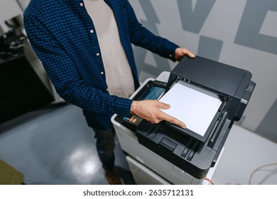 Person using a multifunction printer to copy documents in a modern office environment during daytime hours