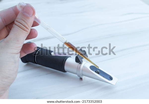 A person using refractometer,\
portable device for the measurement of an index of\
refraction
