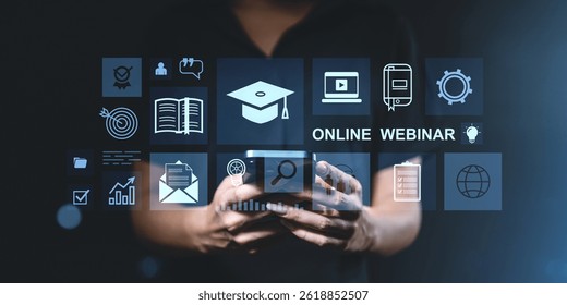 Person using smartphone with digital interface icons related to online webinars and education on dark blurred background, concept of e-learning