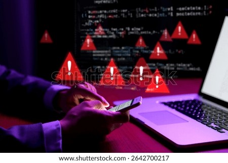 Person using smartphone with multiple red warning triangles and error messages on laptop screen.