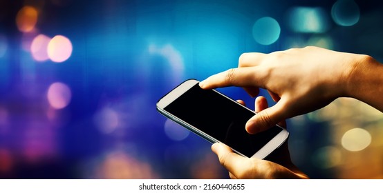 Person using a smartphone on a shiny blue and purple background - Shutterstock ID 2160440655