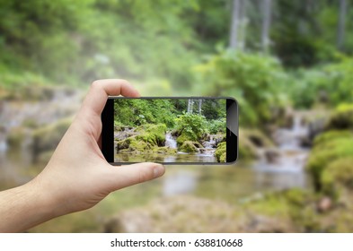 Person using smartphone to photograph waterfall in forest - Powered by Shutterstock